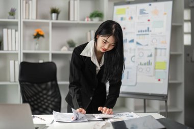 Odaklanmış bir muhasebeci, ofiste önemli bir toplantıya hazırlanırken mali belgeleri gözden geçirir..