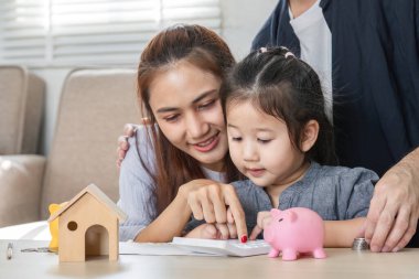 Bir çocuk domuz kumbarasıyla uğraşırken hesap makinesi kullanır, temel finansal becerileri ve tasarruf anlayışını geliştirir.