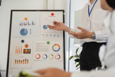 Odaklanmış bir sunum, işbirlikçi bir ofis ortamında grafik ve grafiklerle önemli veri içgörülerini vurgular.