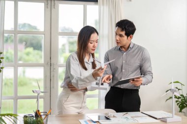 İki iş adamı yenilenebilir enerji projeleri ve ESG girişimleri üzerinde parlak, modern ofis ortamında strateji oluşturuyorlar.