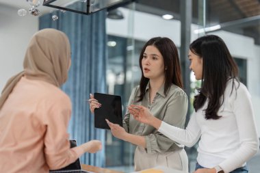 Modern bir ofiste, üç nişanlı kadın ortak bir toplantı sırasında anlayış ve stratejileri paylaşıyor..
