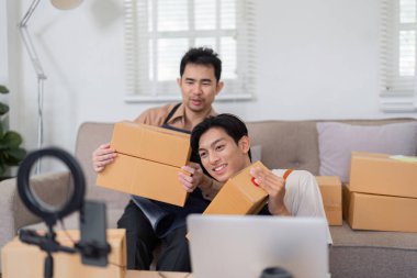 İki farklı çevrimiçi satıcı paketleri düzenliyor ve e-ticaret stratejilerini evde tartışıyor, takım çalışması ve girişimcilik sergiliyor.