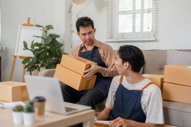 İki farklı genç adam evde birlikte çalışıyor, paketleri düzenliyor ve nakliye için online iş stratejilerini tartışıyorlar..