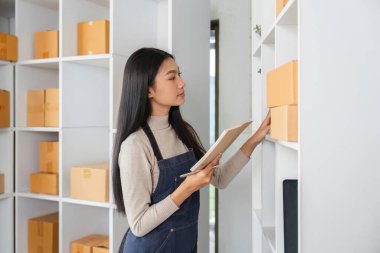 Genç bir kadın envanter kontrolü yapar ve modern depolama alanındaki kayıtları günceller, organizasyon ve verimliliği vurgular.