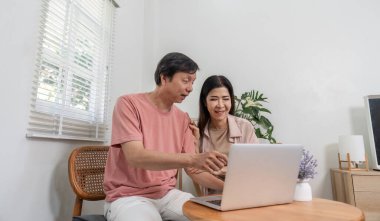 Üst düzey bir çift laptopta birlikte yeni içerikler keşfediyor. Sıcak ve davetkar bir ortamda neşe ve şefkat gösteriyorlar..