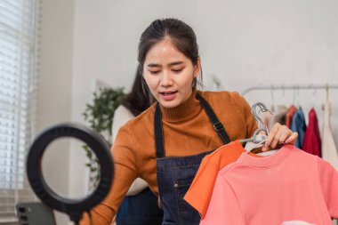 Genç bir bayan girişimci çevrimiçi giyim mağazasını işletiyor, canlı tişörtler sergiliyor ve ürün seçimi ve pazarlama stratejileri uyguluyor..