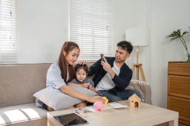 Bir aile, çocuklarına domuz kumbaralarını kullanarak tasarruf yapmayı öğretirken finansal planlama hakkında tartışır..