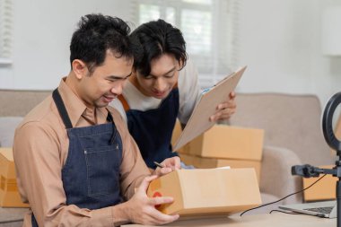 İki online satıcı birlikte çalışıyor, paketleri düzenliyor ve sevkiyat detaylarını tartışıyor, işbirliği ve verimliliği vurguluyor.