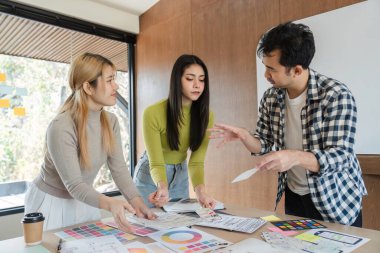 Tasarım kavramları üzerinde işbirliği yapan ve modern bir ofis çalışma alanında geri bildirim tartışan farklı bir profesyonel grup..