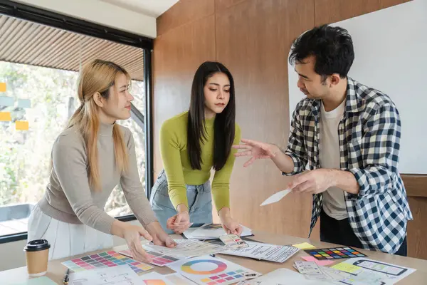 Tasarım kavramları üzerinde işbirliği yapan ve modern bir ofis çalışma alanında geri bildirim tartışan farklı bir profesyonel grup..