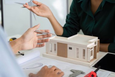 Sürdürülebilir bir yapı modeli üzerinde işbirliği yapan mimarlar, çevre sorumluluğunu ve yenilikçi tasarımı vurguluyorlar.