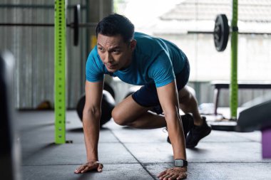 Spor salonunda dağcılık yapan bir adam spor meraklıları için yüksek yoğunluklu kardiyo çalışması yapıyor..