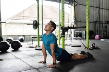 Yoga yapan formda bir adam modern bir spor salonunda esnek ve sağlıklı olmayı teşvik eder. Fitness ve sağlık temaları için ideal.