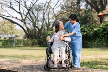 Hemşire ve yaşlı bir hasta bahçede huzurlu bir anı paylaşıyor. Bakım, şefkat ve doğanın güzelliğini vurguluyorlar..