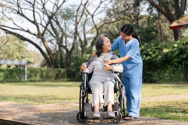 Hemşire ve yaşlı bir hasta bahçede huzurlu bir anı paylaşıyor. Bakım, şefkat ve doğanın güzelliğini vurguluyorlar..