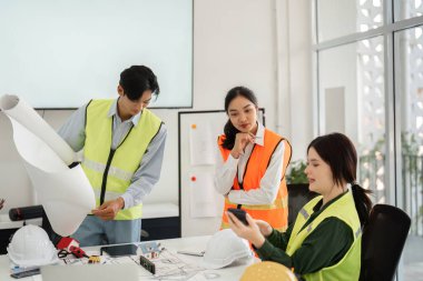 Mimari planları inceleyen ve proje güncellemelerini tartışan çeşitli bir inşaat ekibi modern ofis ortamında etkili bir iletişim sergilediler..