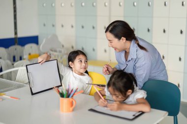 Bir öğretmen çocuklarla canlı bir sınıfta iletişim kurarak, okula hazırlanırken pozitif bir öğrenme ortamı sağlar..