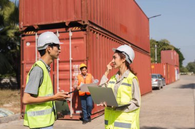 İki inşaat mühendisi proje lojistiği hakkında bir tartışmaya girişirken, bir yönetici de bunların arkasındaki verileri kaydediyor..