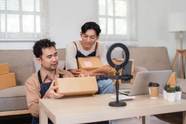 İki genç Asyalı girişimci evlerindeki boks oturumuna hazırlanıyor, ellerinde paketler ve seyircileriyle karşılaşmak için ekipmanlar hazırlıyorlar..