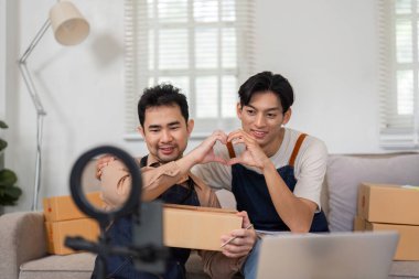 İki genç Asyalı girişimci, canlı bir boks maçı sırasında seyircileriyle uğraşırken elleriyle kalp hareketi yapıyorlar. 