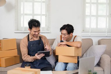 İki adam internetteki iş performanslarını heyecan içinde analiz ediyor. Etrafı kutularla çevrili..