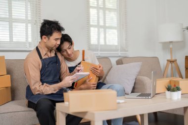 İki sosyal medya pazarlamacısı bir beyin fırtınası oturumunda, biri not alırken diğeri bir ürün paketi tutarken, ev ofislerinde ortak bir atmosfer yaratıyor..