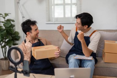 İki hevesli ortak bir ev ofisinde, ürünleri kutulara koyarken heyecanı kutluyor ve paylaşıyorlar, girişimci ruhlarını ve takım çalışmalarını sergiliyorlar..