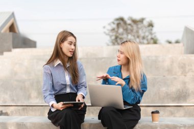 İki farklı iş kadını, ortak bir ortamda dizüstü bilgisayar ve tablet kullanırken stratejiler hakkında bir tartışmaya giriştiler..