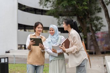 Çeşitli üniversite öğrencilerinden oluşan bir grup açık havada toplandı, tablet kullanırken akademik projeler üzerinde tartıştılar..
