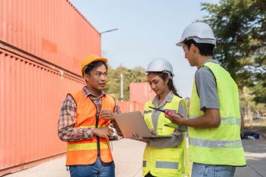 Bir lojistik mühendisliği ekibi, bir inşaat sahasında dizüstü bilgisayarla proje hedeflerini gözden geçirir, takım çalışmasını geliştirir ve hedeflere odaklanır..
