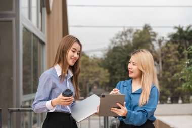 Çağdaş bir ortamda elinde tablet ve kahveyle tartışan iki farklı kadın..