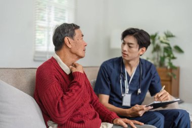 Bir hemşire, sağlık sorunları hakkında konuşurken yaşlı bir hastayı dikkatle dinler ve evde sağlık hizmetleri ortamında açık iletişimi teşvik eder..