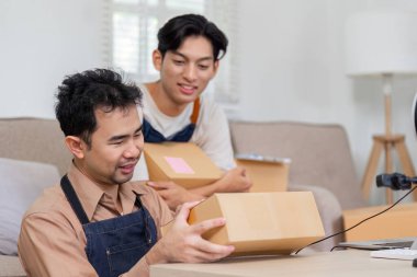 İki hevesli teslimat uzmanı paketleri yan yana inceleyip, iyi aydınlatılmış ve organize bir ofiste çalışırken içgörü ve gülümsemelerini paylaşıyorlar..