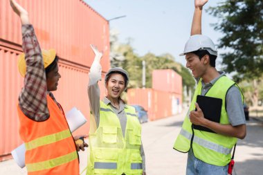 Aralarında bir kadın danışman ve iki erkek işçinin de yer aldığı üç inşaat çalışanı, canlı bir inşaat sahasında proje planları üzerinde işbirliği yaparken başarılarını beşlikle kutluyor..