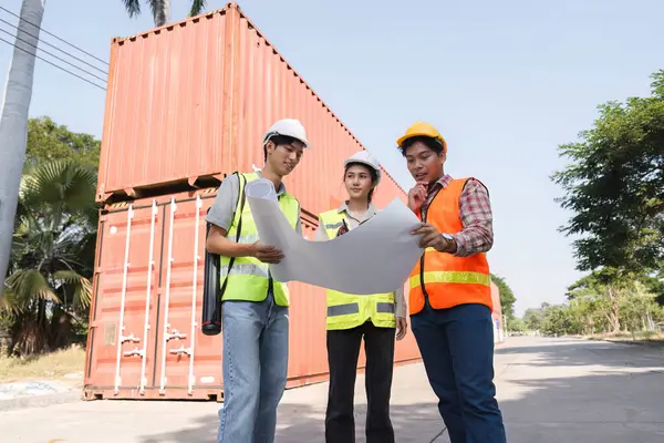 Bir mühendis, bir proje yöneticisi ve bir işçi de dahil olmak üzere çeşitli bir inşaat ekibi planlar üzerinde çalışıyor ve aktif bir şantiyede atılacak sonraki adımları tartışıyorlar..