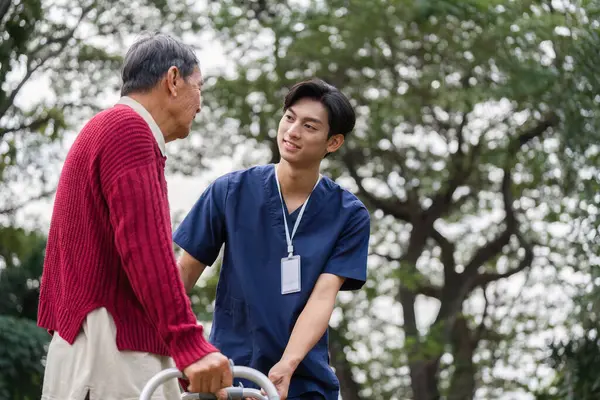 Huzurlu bir açık hava ortamında yaşlı bir adamla şefkatli bir sağlık çalışanı arasında neşeli bir etkileşim, destek ve bağlantı.
