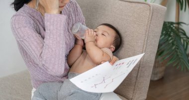 Düşünceli bir anne bebeğini beslerken düşünmek için ara verir. İş ve bakım dengesini sağlayan rahat bir ofis ortamında iş çizelgeleri tutar..