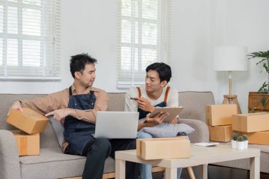 İki dağıtım uzmanı paketler hakkında fikir ve görüşlerini paylaşıyor, biri bir kutu tutuyor, diğeri ise tabletle, parlak ve rahat bir çalışma alanında siparişlerle dolu..