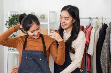 İki genç bayan moda tasarımcısı, bir butikte birlikte çalışmaktan, kıyafet sergilemekten ve fikirlerini paylaşmaktan keyif alıyorlar..