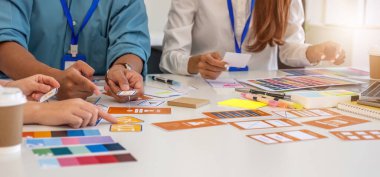 Tasarım uzmanlarından oluşan bir ekip, bir çalışma alanında yaratıcılığı ve yeniliği teşvik ederek, tasarım tasarımları ve renk seçimlerinde işbirliği yapmaktadır..