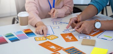 Bir grup profesyonel, ortak bir tasarım toplantısına katılır, tasarım kavramları ve renk paletleri tartışır ve incelenir.