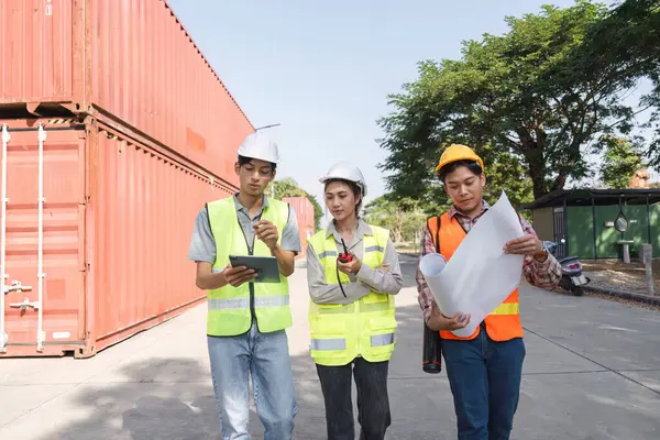 Aralarında bir mühendis, bir proje yöneticisi ve bir işçinin de yer aldığı üç inşaat işçisi, canlı bir şantiyede planlar ve bir tablet kullanarak işbirliği yapıyorlar..
