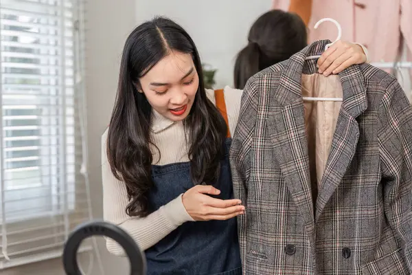 Evlerinde canlı bir atmosfer yaratırken internetten kıyafet satışlarına odaklanan ve modaya uygun ekose ceket giyen iki kadın heyecanlı bir şekilde sunuyor..