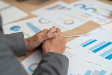 Haritaları ve grafikleri inceleyen, finansal performans ve stratejiye odaklanan bir iş adamı.