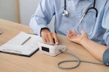 Bir doktor, bir hastanın sağlığını ölçmek için kan basıncı monitörü kullanır ve klinik ortamda kapsamlı muayeneyi vurgular..