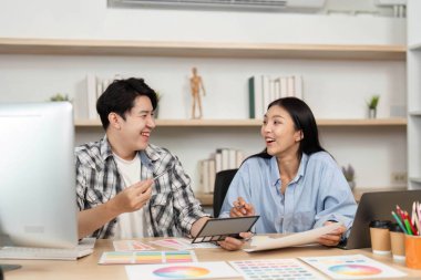 İki genç profesyonelin UI ve UX 'in tablet ve renk grafikleri kullanarak fikir ürettiği ortak bir atmosfer..