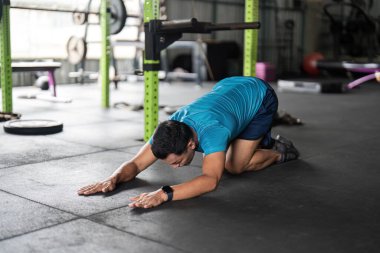 Spor salonunda vücut egzersizi yapan bir adam modern bir spor salonunda forma ve dayanıklılık eğitimine olan bağlılığını sergiliyor..