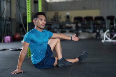 Formda bir adam spor salonunda esneme egzersizi yapar. Modern bir spor salonunda esneklik ve uygunluğu teşvik eder..