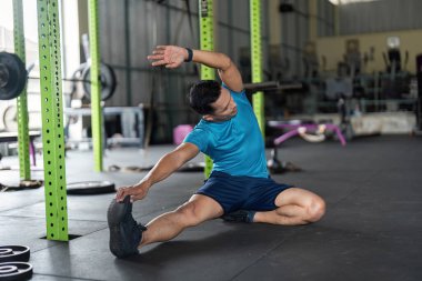 Genç bir adam kenar esneme egzersizi yapar, esnekliği arttırır ve fitness merkezinde sağlıklı bir yaşam tarzını teşvik eder..