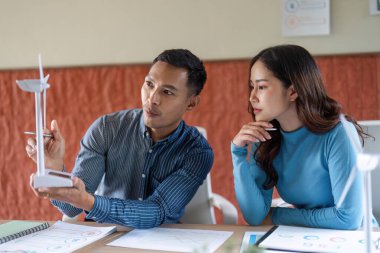 Bir erkek ve kadın, yenilenebilir enerji çözümleri hakkında verimli bir tartışma içinde, bir şirket ortamında ESG ilkeleri sergiliyorlar..